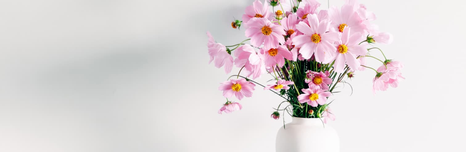 Vase with different foliage. Some flowers on the left and right are drooping. The middle ones are standing up.